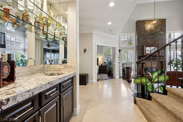 bar featuring ornamental molding, dark brown cabinets, ceiling fan, sink, and decorative light fixtures