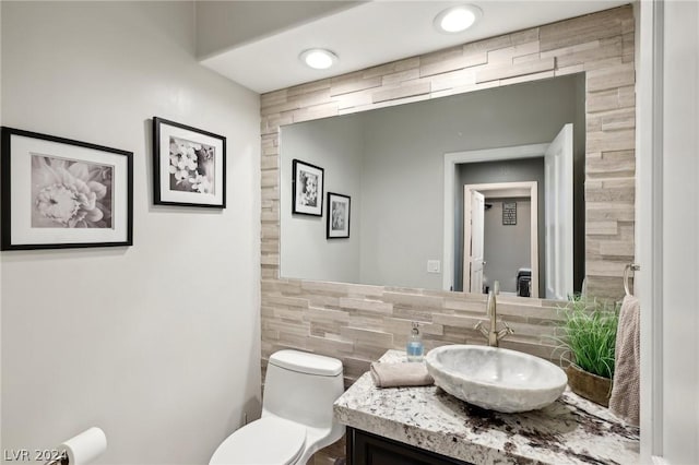 bathroom with vanity, tile walls, and toilet