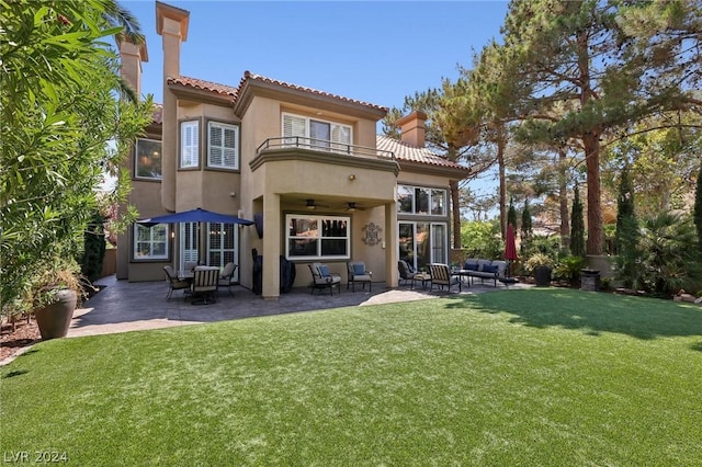 rear view of property with a lawn, a patio area, ceiling fan, and a balcony