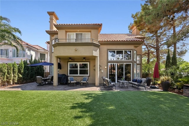 rear view of property with a lawn, ceiling fan, a balcony, and a patio