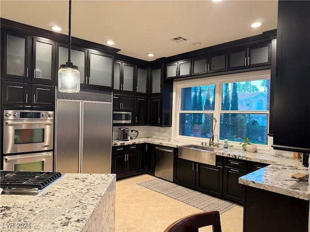 kitchen featuring pendant lighting, sink, light stone countertops, light tile patterned flooring, and stainless steel appliances