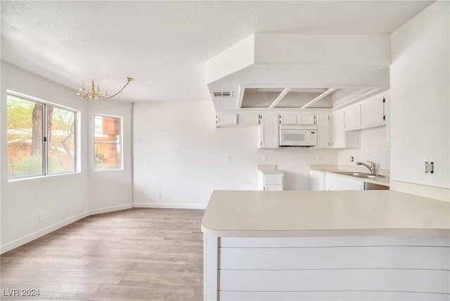 845 Mesquite Springs Dr Unit 101, Mesquite, NV 89027 - kitchen with an inviting chandelier, a sink, white cabinets, light wood-type flooring, and white microwave
