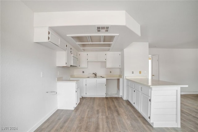 845 Mesquite Springs Dr Unit 101, Mesquite, NV 89027 - kitchen with a sink, a peninsula, white microwave, visible vents, and light wood-style flooring
