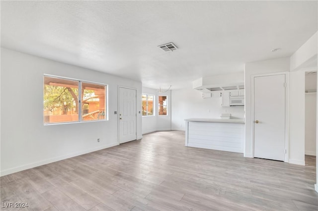 845 Mesquite Springs Dr Unit 101, Mesquite, NV 89027 - unfurnished living room featuring a chandelier, visible vents, light wood-style flooring, and baseboards