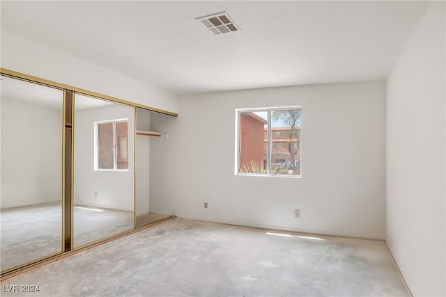 unfurnished bedroom with concrete flooring and a closet