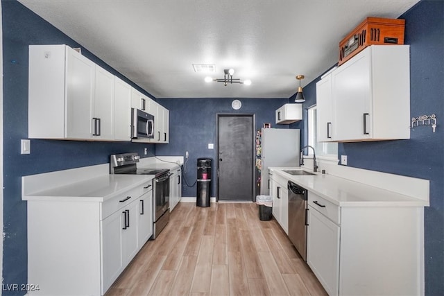 kitchen featuring white cabinets, pendant lighting, sink, appliances with stainless steel finishes, and light hardwood / wood-style floors