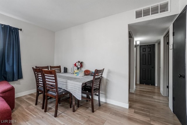 dining room featuring an inviting chandelier, light hardwood / wood-style floors, and a textured ceiling