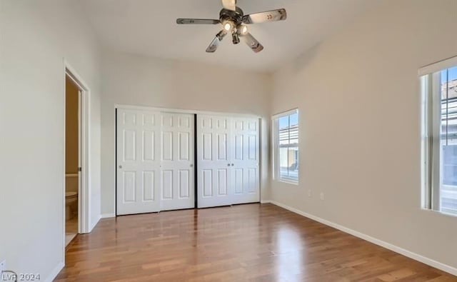 unfurnished bedroom with ceiling fan, multiple windows, and hardwood / wood-style flooring