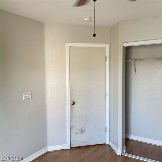 unfurnished bedroom featuring a closet, hardwood / wood-style floors, and ceiling fan