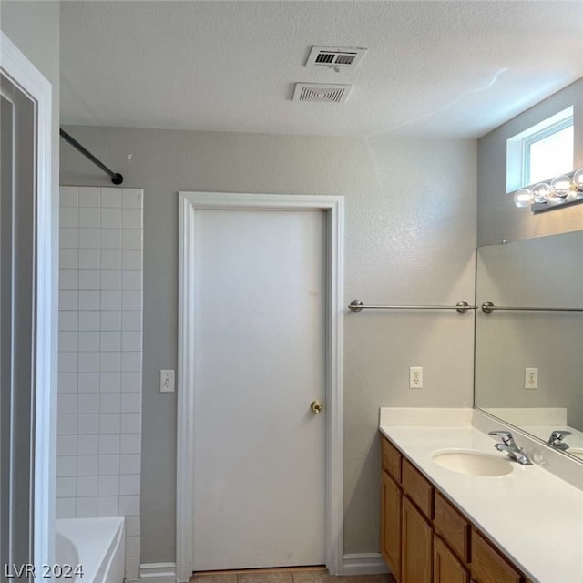 bathroom featuring tile patterned flooring, bathing tub / shower combination, vanity, and a textured ceiling