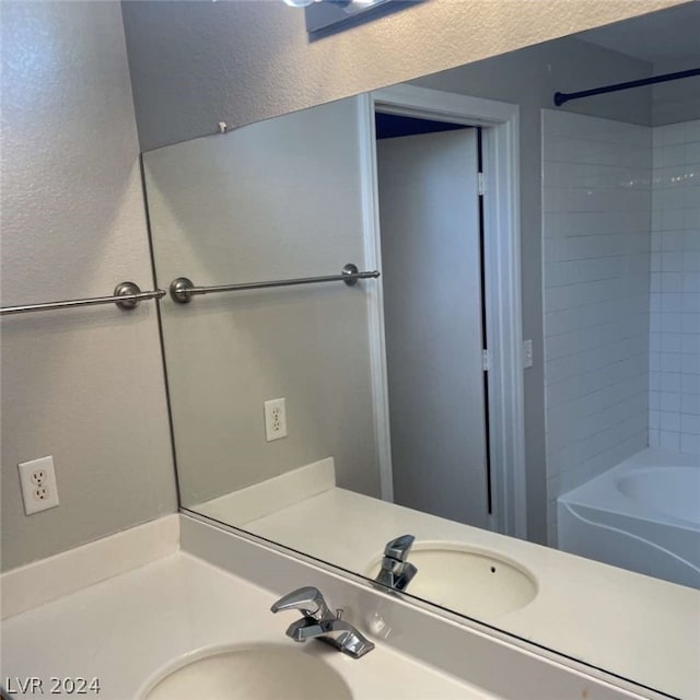 bathroom with tiled shower / bath combo and vanity