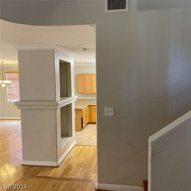 hall featuring light tile patterned flooring, crown molding, and a notable chandelier