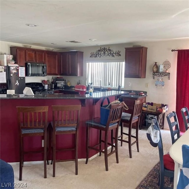 kitchen featuring light colored carpet, kitchen peninsula, and black appliances