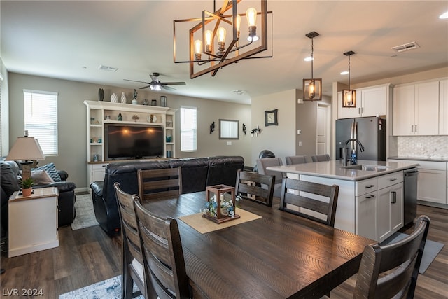 dining room with ceiling fan with notable chandelier, dark hardwood / wood-style flooring, and sink