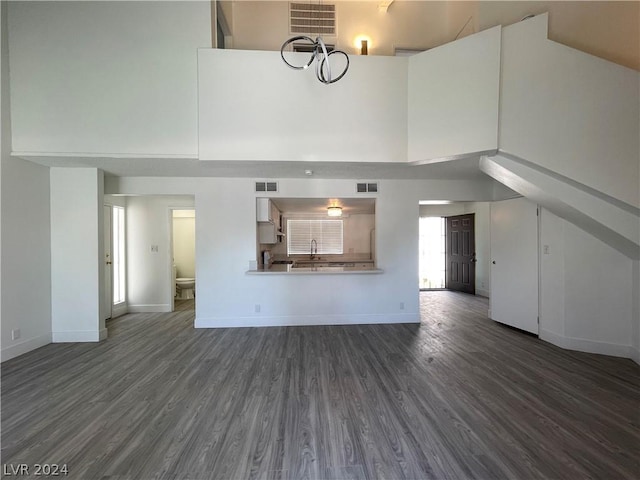 unfurnished living room with a towering ceiling, dark hardwood / wood-style flooring, and sink