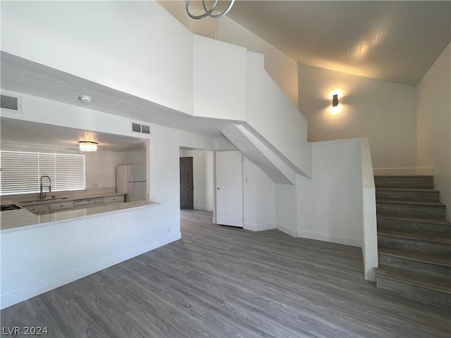 unfurnished living room with dark hardwood / wood-style flooring, sink, and high vaulted ceiling