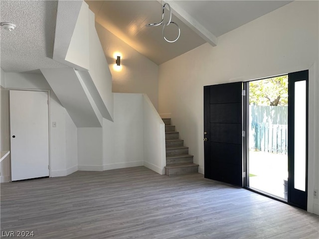 interior space featuring light wood-type flooring and vaulted ceiling with beams