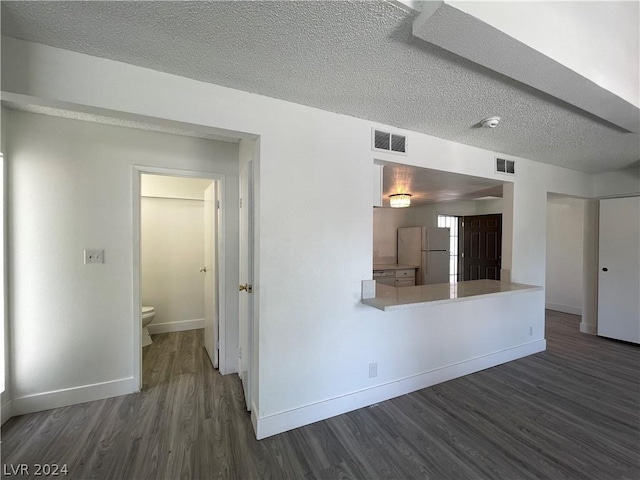 kitchen with white fridge, dark hardwood / wood-style floors, and a textured ceiling