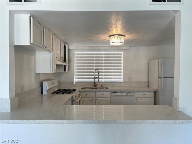 kitchen featuring white cabinetry, white appliances, light stone countertops, and sink