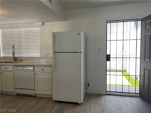 kitchen featuring white cabinetry, sink, white appliances, and light wood-type flooring