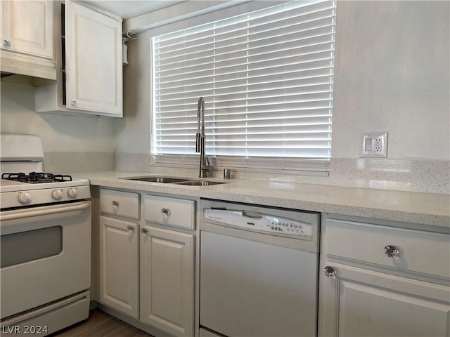 kitchen featuring white appliances, a healthy amount of sunlight, sink, and white cabinets