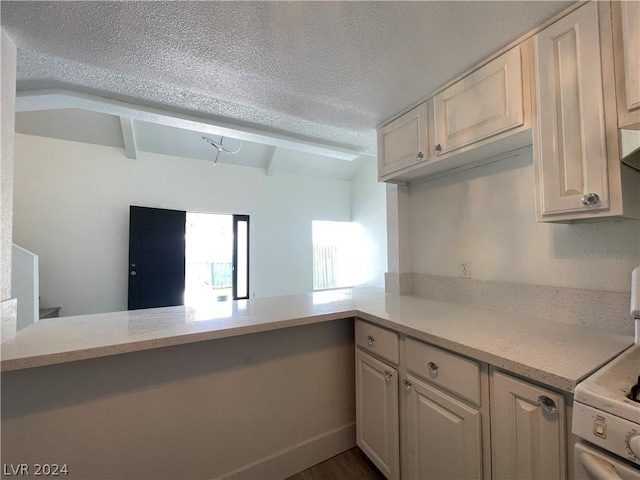 kitchen with kitchen peninsula, beam ceiling, light stone counters, white stove, and a textured ceiling