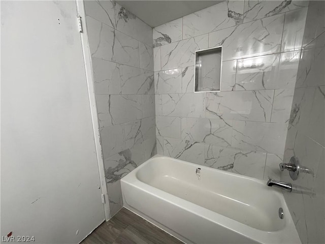 bathroom with hardwood / wood-style flooring and tiled shower / bath