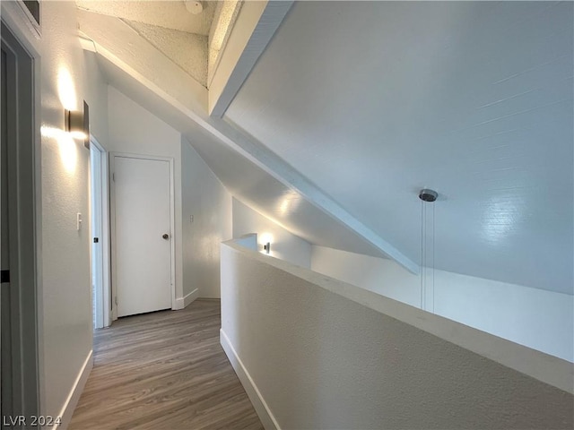 hallway with lofted ceiling and hardwood / wood-style floors