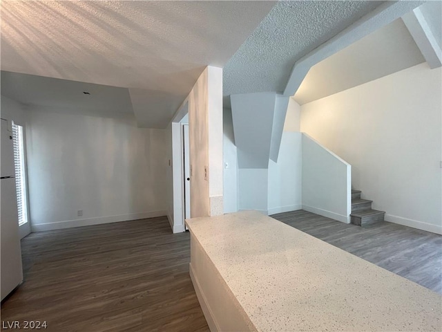 bonus room with dark hardwood / wood-style floors and a textured ceiling