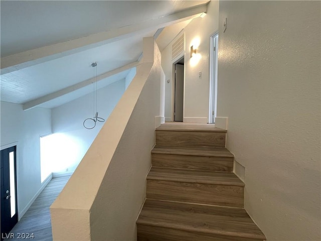 stairs featuring hardwood / wood-style floors and vaulted ceiling with beams