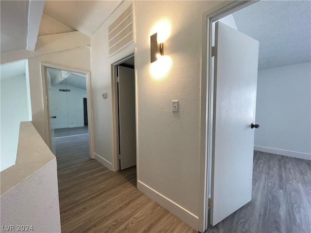 corridor with dark wood-type flooring and vaulted ceiling