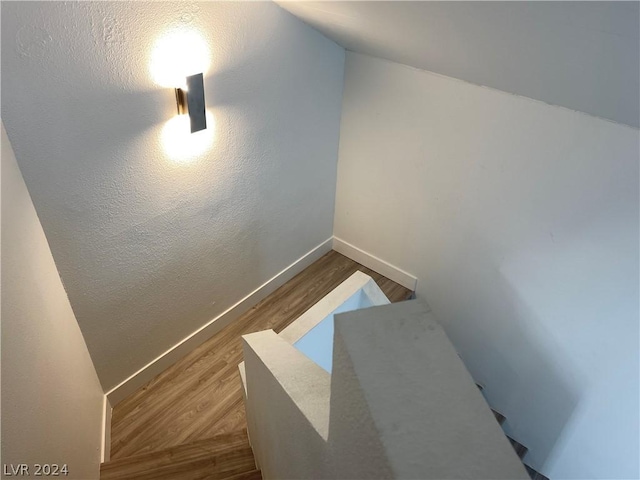 stairway featuring hardwood / wood-style flooring and lofted ceiling