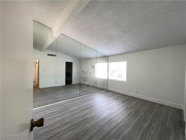 unfurnished bedroom with dark hardwood / wood-style flooring, lofted ceiling with beams, and a textured ceiling