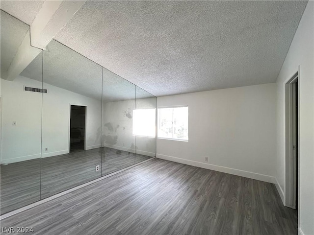 unfurnished bedroom with dark hardwood / wood-style floors, vaulted ceiling, and a textured ceiling