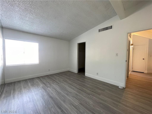 unfurnished room with dark hardwood / wood-style flooring, vaulted ceiling, and a textured ceiling