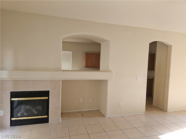 unfurnished living room with a tiled fireplace and light tile patterned floors