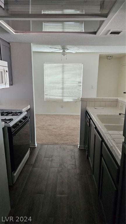 kitchen featuring dark hardwood / wood-style floors, ceiling fan, sink, and gas range oven