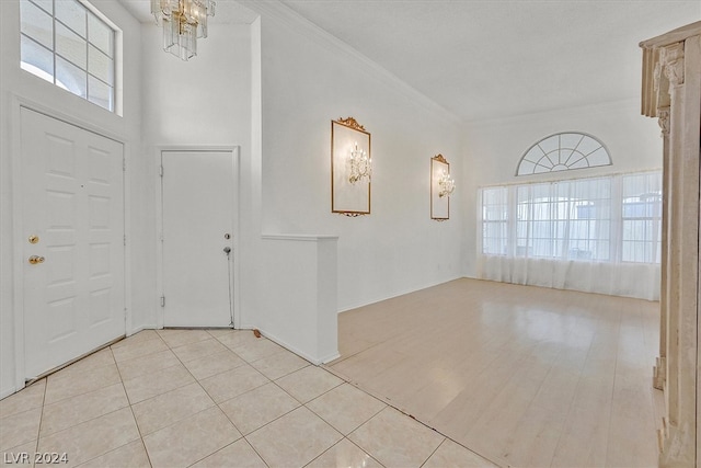 foyer entrance featuring a high ceiling, a notable chandelier, ornamental molding, and light tile patterned flooring