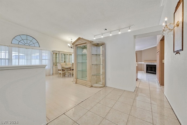 corridor featuring light tile patterned floors, an inviting chandelier, and ornamental molding