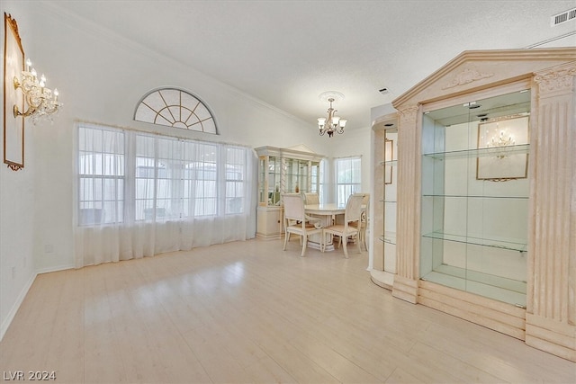 unfurnished dining area with a chandelier, wood-type flooring, a textured ceiling, and crown molding