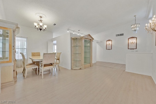 dining area with crown molding, light hardwood / wood-style floors, a textured ceiling, and an inviting chandelier