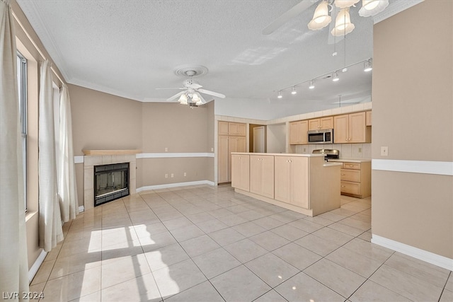 kitchen featuring light brown cabinets, crown molding, light tile patterned floors, a textured ceiling, and stainless steel appliances