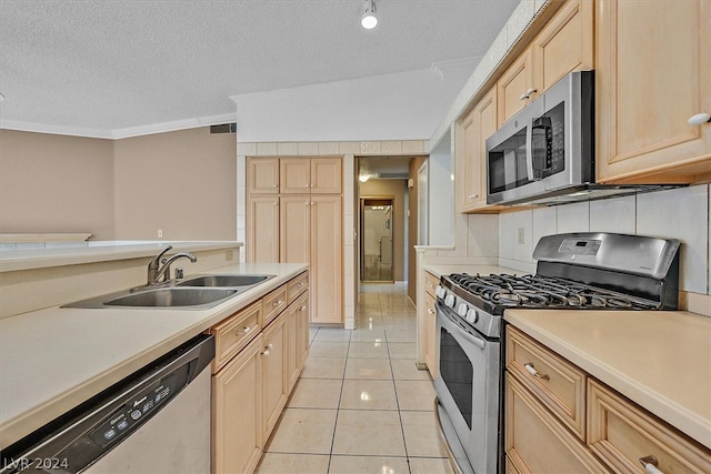 kitchen with sink, light tile patterned floors, a textured ceiling, and appliances with stainless steel finishes