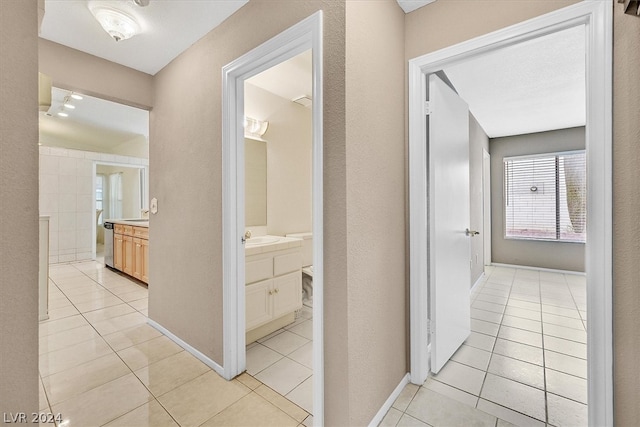 corridor with light tile patterned flooring and sink