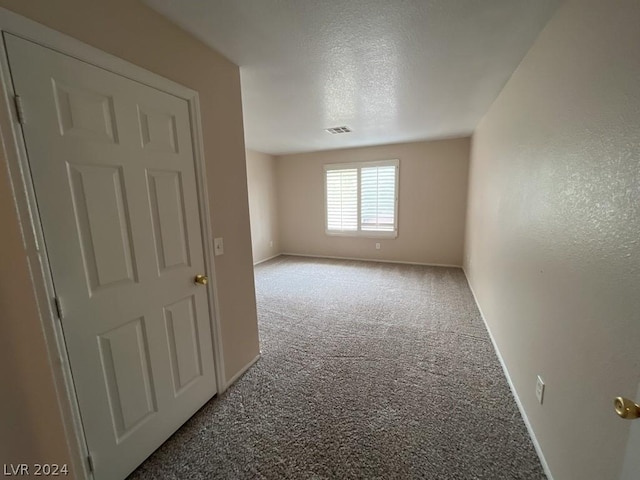 unfurnished room featuring carpet and a textured ceiling