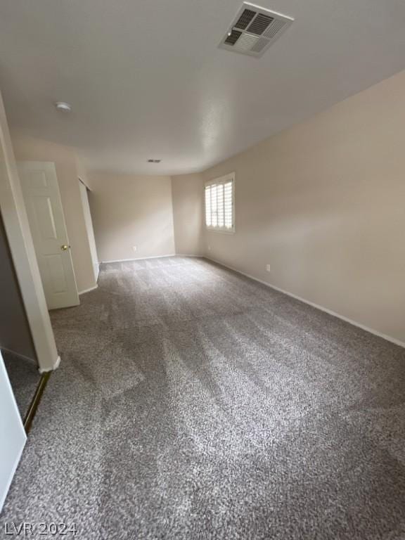 unfurnished room featuring dark colored carpet