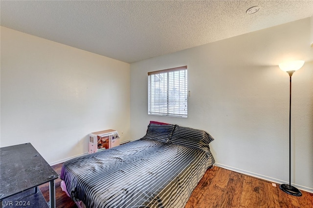 bedroom with wood-type flooring and a textured ceiling