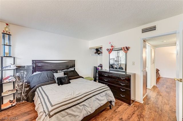 bedroom with light hardwood / wood-style floors and a textured ceiling