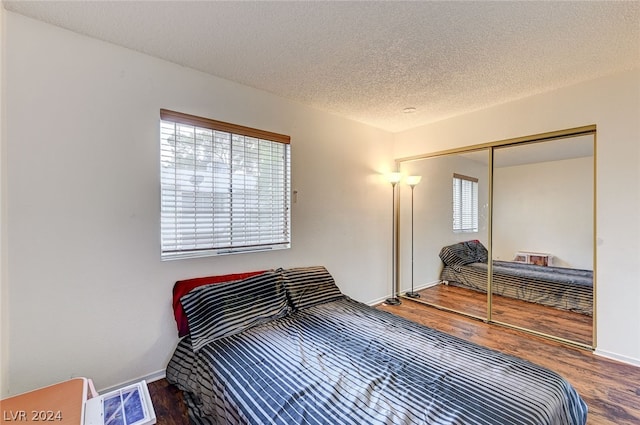 bedroom with a textured ceiling, a closet, and hardwood / wood-style floors