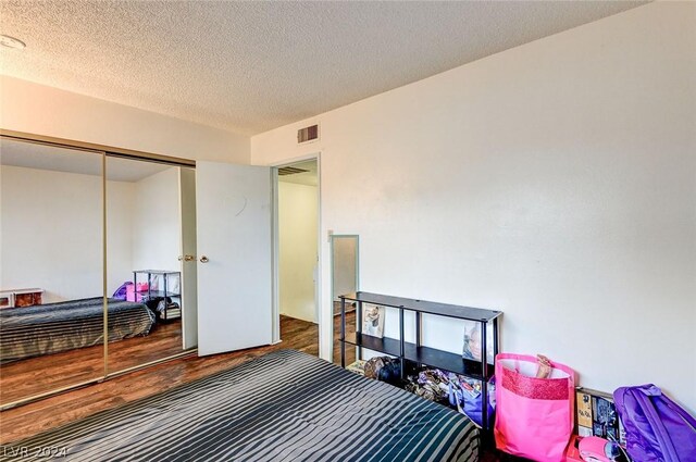 bedroom featuring a closet, hardwood / wood-style floors, and a textured ceiling